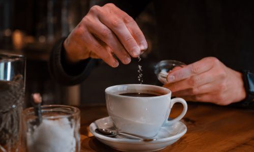 Pitada de sal sendo adicionada a uma xícara de café preto