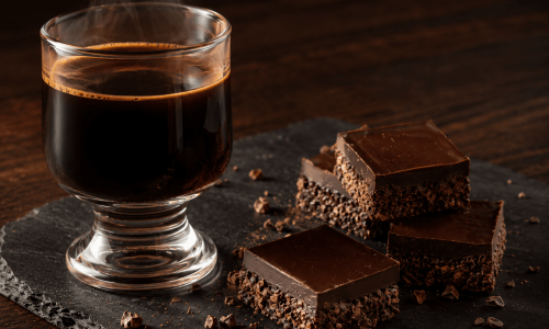 Café especial com quadrados de chocolate escuro sobre mesa de madeira