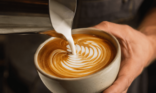 Leite de aveia sendo vertido no café para criar latte art